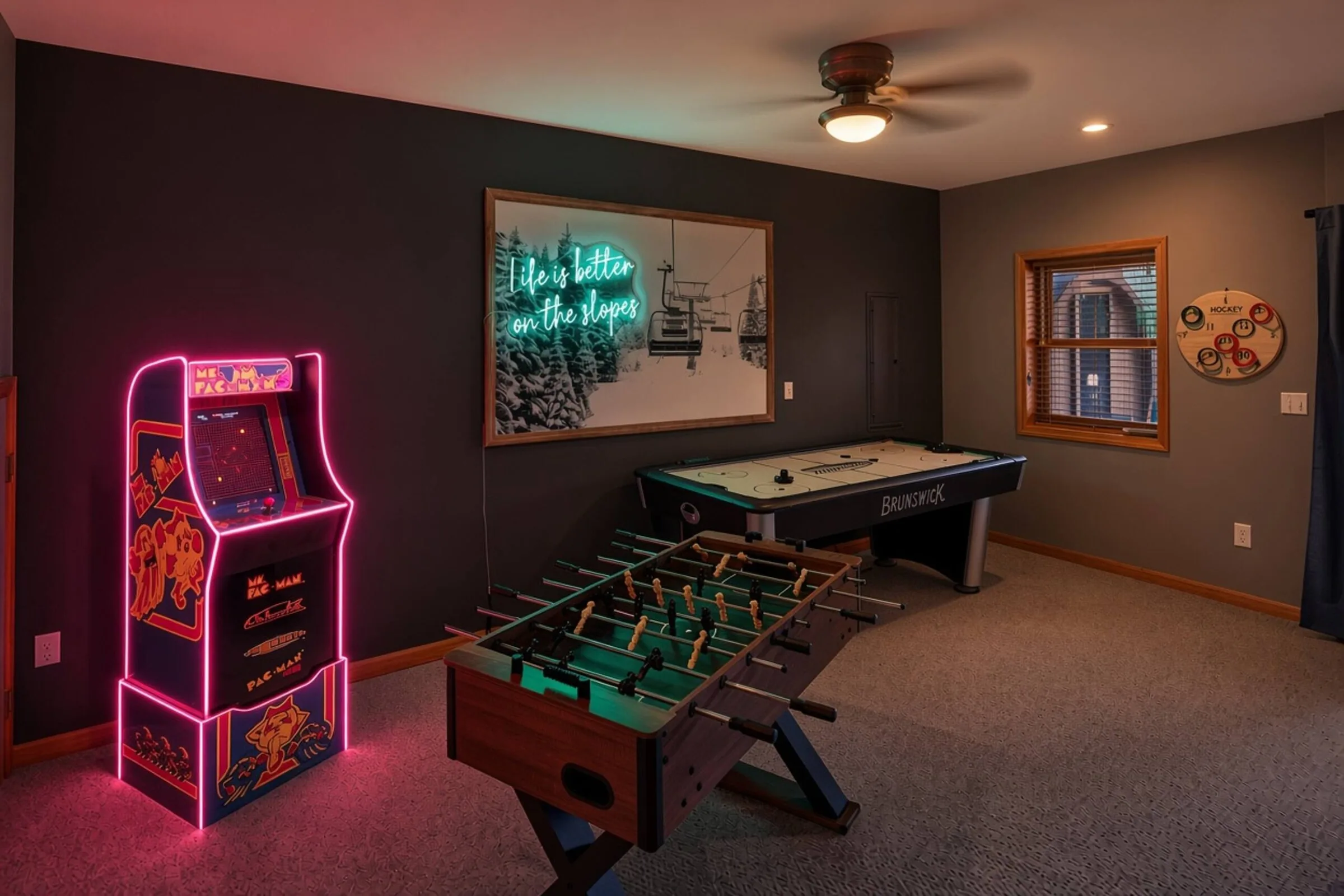 Game room at night, the arcade cabinet lit up beside the foosball table
