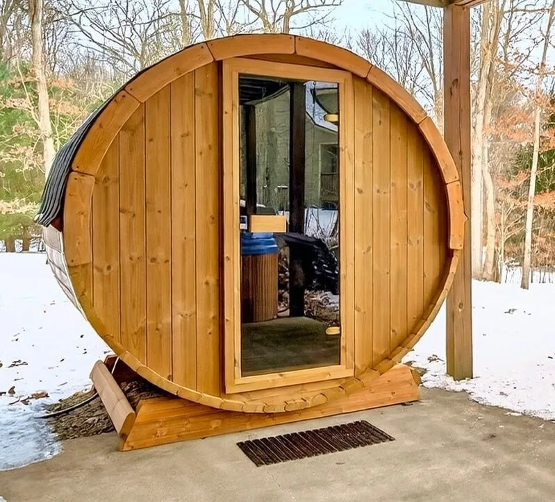 Finnish barrel sauna in the snow behind the house